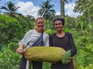 um homem e uma mulher segurando um grande pedaço de fruta em Farmstay Manangel em Sindanglaka