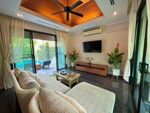 uma sala de estar com um sofá e uma televisão de ecrã plano em The Kiri Villas Resort em Thalang