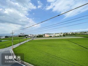 a field of green grass next to a road at 稻嶼天光包棟民宿 in Yilan City