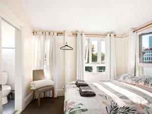 a bedroom with a bed and a chair and windows at Lord Wolseley Hotel in Sydney