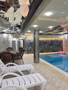 a swimming pool with white lounge chairs and a swimming pool at HAYAT PLAZA HOTEL & Spa in Samarkand