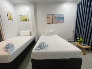 2 camas en una habitación con paredes blancas en Mother’s House, en Battambang