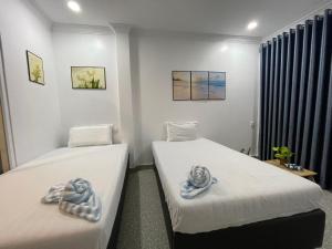 Dos camas en una habitación con toallas. en Mother’s House en Battambang