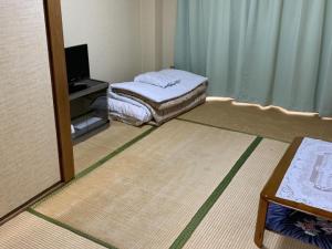 a small room with a bed and a television at Imazato Ryokan in Osaka