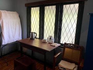 um quarto com uma secretária, uma cadeira e janelas em OM Homestay em Bentota