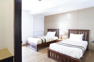 um quarto com 2 camas e lençóis brancos em Nanatai Suites em Bangkok