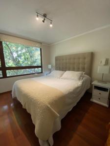 a bedroom with a large white bed and a window at Departamento Las Condes Mall Sport in Santiago
