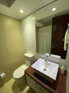 een badkamer met een wastafel, een toilet en een spiegel bij Departamento Las Condes Mall Sport in Santiago