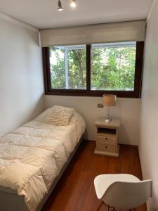 a bedroom with a bed and a chair and a window at Departamento Las Condes Mall Sport in Santiago