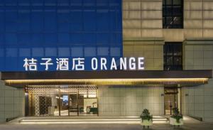 Orange Hotel - Taicang Nanyang Plaza في Taicang: مدخل لمبنى مكتب مع لوحة مكتوب عليها برتقال