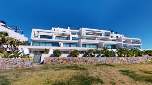 ein großes weißes Gebäude mit einer Steinmauer in der Unterkunft Las Colinas Golf, luxury penthouse in Orihuela