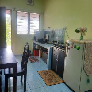 a kitchen with a refrigerator and a table in it at Homestay sunnah bougainvillea resident Islam 