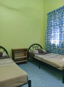 a room with two beds and a table at Homestay sunnah bougainvillea resident Islam 