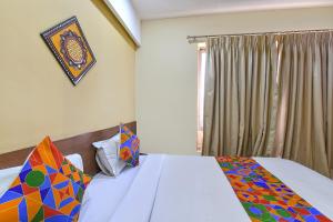 a bedroom with a bed with colorful pillows and a window at FabHotel RB Residency in Surat