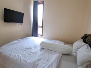 1 dormitorio con 1 cama blanca y TV en la pared en Hotel Dinar Family, en Yakarta