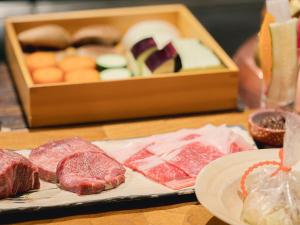 a table with meat and cheese and a box of food at The Luigans Spa and Resort in Fukuoka