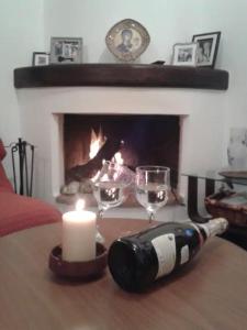 - une bouteille de vin et des verres sur une table devant une cheminée dans l'établissement Lefkogia Cottage, à Lefkogeia