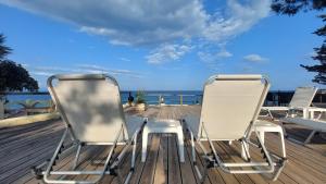 two chairs sitting on a deck looking out at the ocean at Silis House on the beach in Artemida