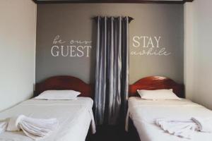 two beds in a room with a sign that says be our guest stay awhile at DaViKa Hotel in Vientiane