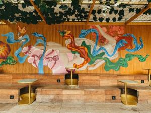 een muurschildering op de muur van een kamer met twee tafels bij Mr A Hotel in Bandung