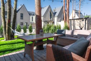 a patio with a table and chairs and a hammock at Žalia kopa with pool in Palanga