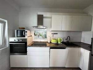La cuisine est équipée de placards blancs et d'un four avec plaques de cuisson. dans l'établissement Apartment Juric NeVi, à Malinska