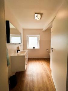 ein leeres Badezimmer mit einem Waschbecken und einem Spiegel in der Unterkunft Modern Apartment Wissenbach 2 in Eschenburg