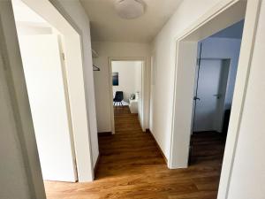 einen Flur eines Apartments mit weißen Wänden und Holzböden in der Unterkunft Modern Apartment Wissenbach 2 in Eschenburg