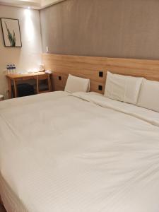 a bedroom with a large white bed with a wooden headboard at Fooyee Hotel - Yonghe in Yonghe