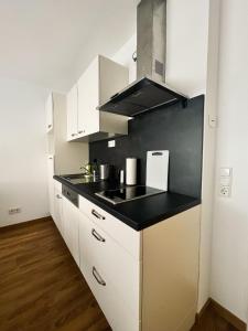cocina con armarios blancos y encimera negra en Modern Apartment Wissenbach 2, en Eschenburg