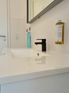 ein weißes Badezimmer mit einem Waschbecken und einem Spiegel in der Unterkunft Modern Apartment Wissenbach 2 in Eschenburg