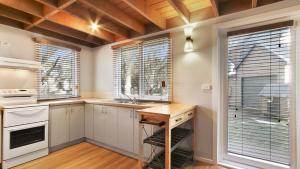 a kitchen with white cabinets and a table and windows at Paddys in Dinner Plain +3 photos