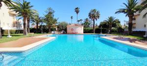 a large swimming pool with palm trees and a building at Apartamento La Marina by DENIA COSTA in Denia