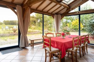 comedor con mesa roja y sillas en Magnifique longère bretonne., en Lanmeur