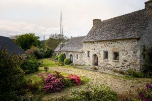 una vieja casa de piedra con flores en el patio en Magnifique longère bretonne., en Lanmeur