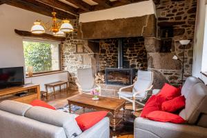 una sala de estar con sofás y una chimenea de piedra. en Magnifique longère bretonne., en Lanmeur