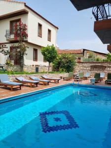 a pool in front of a building with chairs and a house at Sezgin Boutique Hotel in Kusadası