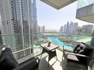 balcón con mesa, sillas y vistas a la ciudad en Luxurious 3 Bedroom Apartment with Burj Khalifa & Fountain View by Luxstay Holiday Homes, en Dubái
