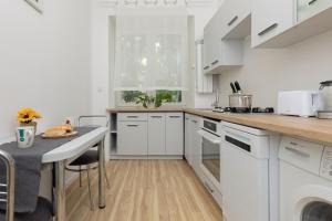 una cocina con armarios blancos y una mesa pequeña. en Bright Apartment Wola near Metro Station by Renters, en Varsovia