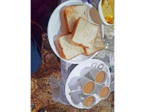 dois pratos brancos de pão e uma tigela de ovos em Hotel Diamond Vihar, Rajgir em Rajgir