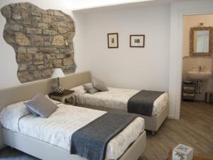 a bedroom with two beds and a stone wall at Al San Lorenzo in Bergamo