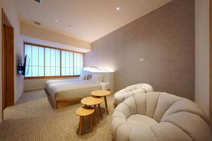 a hotel room with a bed and two chairs at MURE Beppu in Beppu +78 photos