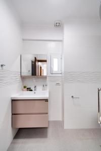uma casa de banho branca com um lavatório e um espelho em Peratzada apartments em Vasiliki