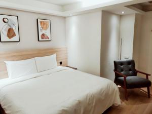 a bedroom with a bed and a black chair at Fooyee Hotel - Yonghe in Yonghe