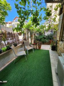 un patio con 2 sillas y un césped verde en house with a garden In the center of Nachlaot, en Jerusalén