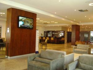 a lobby with two chairs and a television on a wall at Boa Viagem 420 Apart Hotel in Recife