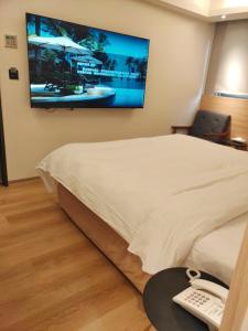 a hotel room with a bed with a television on the wall at Fooyee Hotel - Yonghe in Yonghe