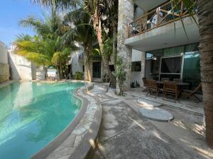 a swimming pool in front of a house with palm trees at Departamento El Cardumen in Chicxulub