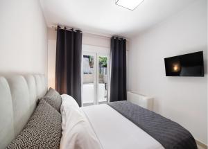 a bedroom with a bed and a tv and a window at Peratzada apartments in Vasiliki