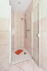La salle de bains est pourvue d'une douche et d'une serviette orange. dans l'établissement Nah am Strand in Bensersiel, Wooge 45, à Esens